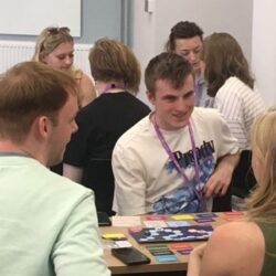 A photo of students sitting around a table playing the Team Work Training Board Game