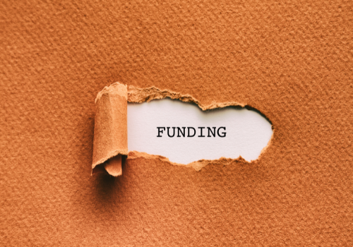 Image of brown paper peed back revealing the word 'funding' on white paper